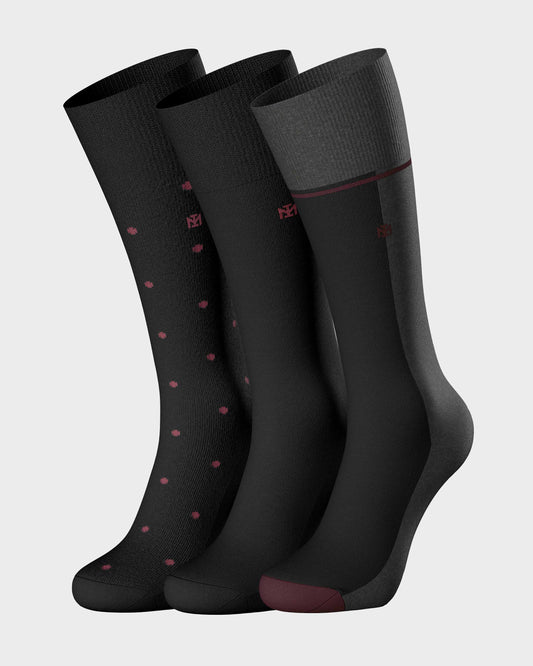 Three pairs of black socks with red accents on a light gray background